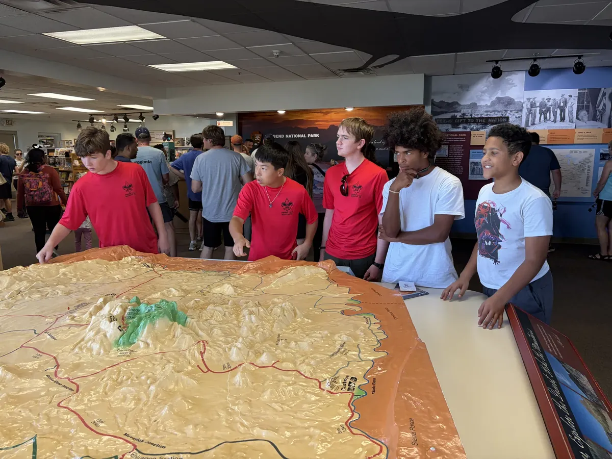 Scouts gathered around a raised-relief map inside a visitor center.