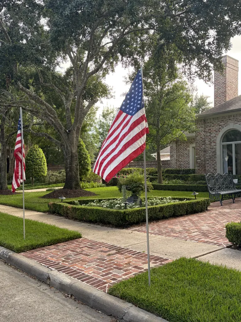 Two American flags placed by Troop 1513 along a Clear Lake front yard.