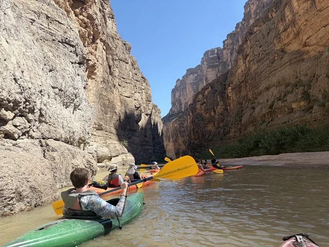 Troop 1513 Scouts kayaking together between tall canyon walls in Big Bend