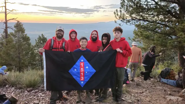 Troop 1513 Scouts and leaders holding their troop flag after a mountain hike