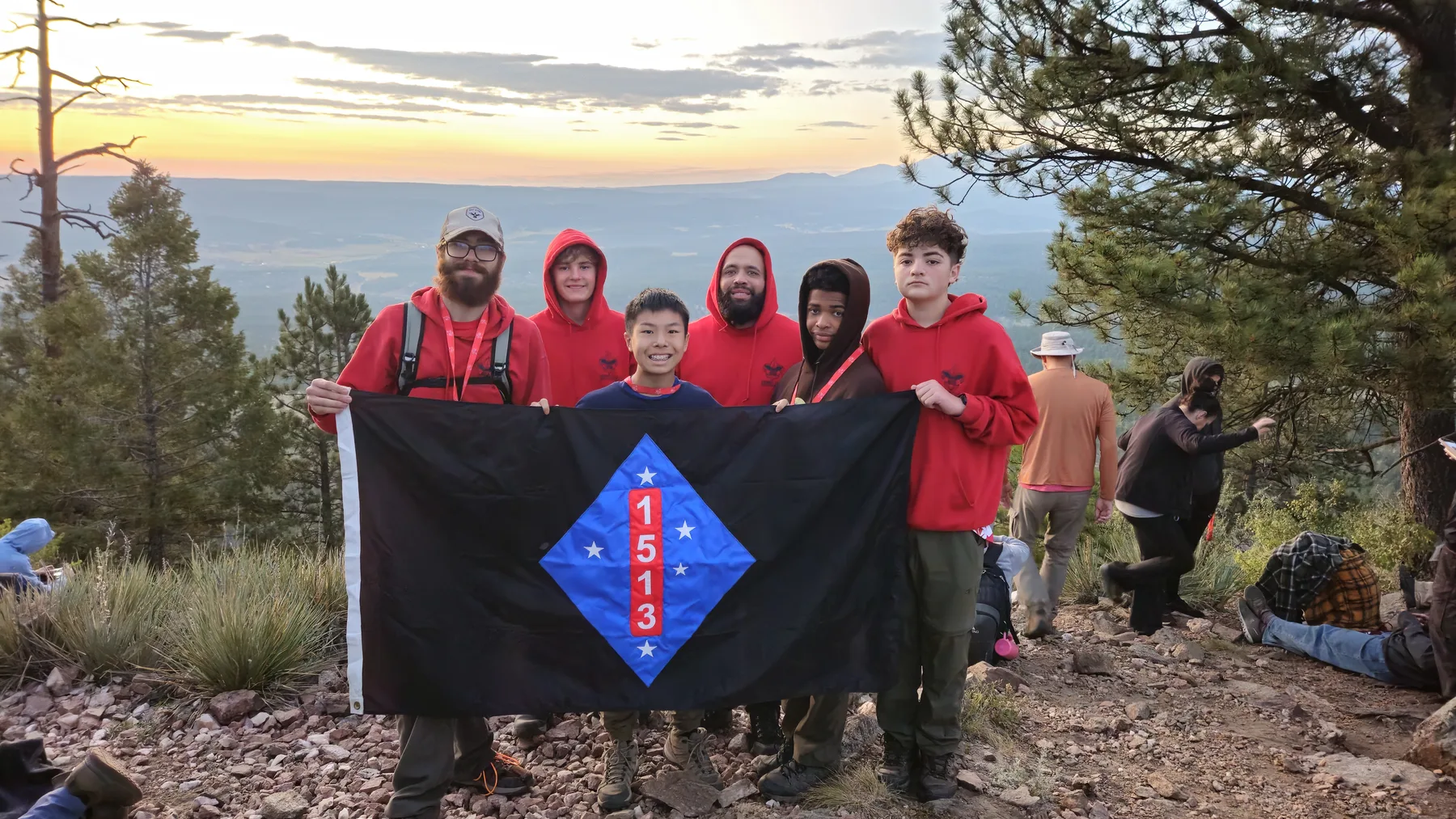 Troop 1513 Scouts and leaders holding their troop flag after a mountain hike